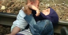 Pictures: Desperate mother clings to her baby as police try to bring migrants to camps