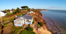 Cliff's edge: Aerial footage shows how couple's home is being slowly reclaimed by sea