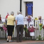People read floral tributes left for Alex Higgins on Belfast's Donegal Road where his funeral cortege will pass along on it's way to St Anne's Cathedral where the funeral service will be held tomorrow.