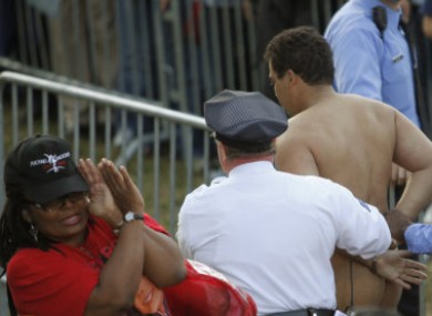 Juan J Rodriquez is escorted from the rally on Sunday. His streaking stunt earned at least one onlooker's disapproval.