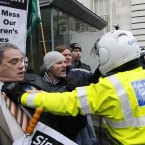 Aengus Ó Snodaigh is held back by a motorbike police at the gates at government buildings. (AP Photo/Peter Morrison)