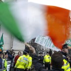 A Sinn Fein protestor waves a tricolour outside government buildings. (AP Photo/Peter Morrison)