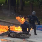 The fire from a Molotov cocktail thrown on a riot police officer in Athens, Greece during this week's protests is damped down by a colleague. Pic: PA Images/Demotix