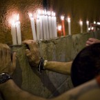 People say good bye with candles as they react in front of a wall, singing the song