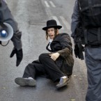 An Ultra-Orthodox Jew falls down while running away from security forces moving in to clear a demonstration against a municipal parking lot that is open on the Jewish Sabbath, in Jerusalem on 16 July, 2011. Ultra-Orthodox activists have repeatedly staged protests since the parking lot opened two years ago, saying operating it on a Saturday is a desecration of the Sabbath, Judaism's biblically-mandated day of rest. (AP Photo/Ben Curtis)