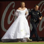 A man who ran onto the field wearing a wedding gown during a baseball game between the Atlanta Braves and the Washington Nationals is led away by an Atlanta police officer in Atlanta on 16 July, 2011. (AP Photo/John Bazemore)