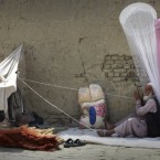 An Afghan street vendor man sells insect nets and brooms, as he twines cord while waiting for customers in Kabul, Afghanistan, on 17 July, 2011. (AP Photo/Musadeq Sadeq)