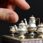 A curator examines a miniature tea set 1cm in height, made by Russian goldsmith Peter Carl Fabergé (Dominic Lipinski/PA Wire)