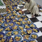 A volunteer arranges plates for people gathered to break their fast during Ramadan in Rawalpindi, Pakistan (AP Photo/B.K.Bangash)