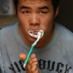 22-year-old armless boy Wu Jianping brushes his teeth using his feet in Zhengzhou, China. Wu has just been admitted to university (Photo by Chen Xiaodong/ChinaFotoPress)