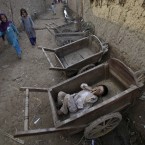 A boy sleeps inside a wooden cart in a slum on the outskirts of Islamabad, Pakistan (AP Photo/Muhammed Muheisen)
