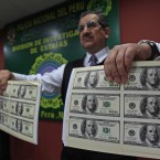 A police officer presents a sample of the nearly two million confiscated dollars in counterfeit US$100 bills in Lima, Peru (AP Photo/Martin Mejia)