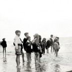 Group of children at the beach, paddling in shallow water. Courtesy of the National Library of Ireland.