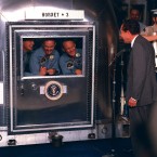 President Nixon welcomes the astronauts aboard the USS Hornet. The three men are pictured inside a quarantine facility on board the ship to prevent the spread of any potential lunar contagions. (NASA)