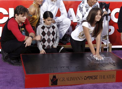 Paris Jackson presses the glove into cement as her brothers look on.
