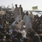 People post for pictures by the shark's carcass in Karachi, Pakistan yesterday. (AP Photo/Shakil Adil/PA Images)