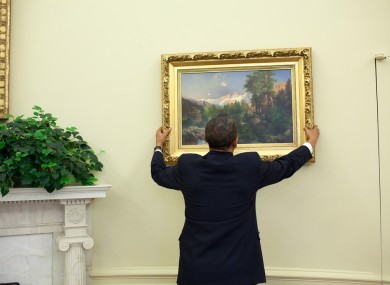 President Obama straightens another painting, Thomas Moran's 'The Three Tetons' in the Oval Office.