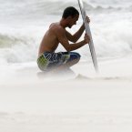 Jesse Deese uses his skim board to shield from blowing sand in Panama City Beach, Florida, as tropical storm Debby raked the Tampa Bay area with high wind and heavy rain Monday. (AP Photo/Dave Martin)