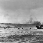 Under the cover of naval shell fire, American infantrymen wade ashore from their landing craft during the initial Normandy landing operations in France. (AP Photo/Peter Carroll)