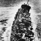 A US Coast Guard craft, heavily listing to port, moves alongside a transport ship to evacuate her troops, during the initial Normandy landing operations. (AP Photo)