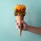 Steak, pickles, lettuce, fried onions, cheddar cheese on an ice-cream cone.