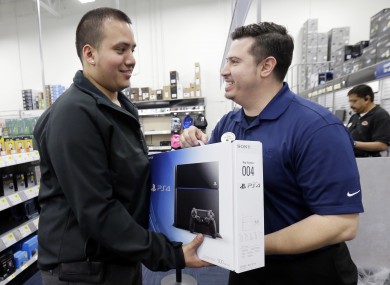 Andy Varadez, left, from Chicago, purchases a Sony PlayStation 4 from Best Buy sales manager Michael Centeno. 
